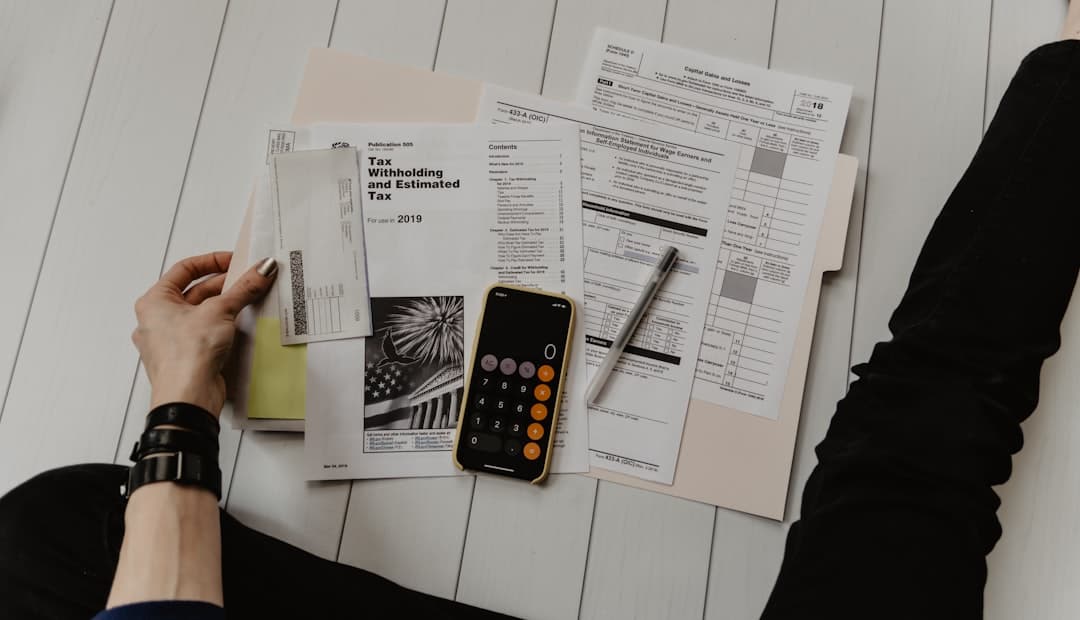 Small business owner reviewing contractor payment records at a desk with a calculator and tax forms