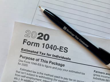 Small business owner reviewing tax documents and 1099 forms at desk with calculator