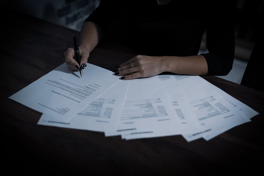 Small business owner reviewing contractor documents at a desk with a globe and tax forms nearby
