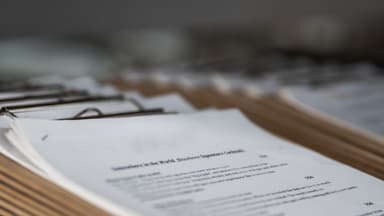 Business professional reviewing contractor documents and updating records at desk