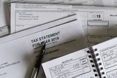 Frustrated small business owner reviewing IRS penalty notices and tax documents at desk