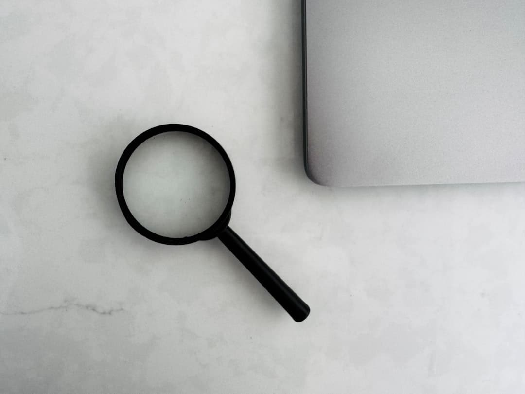 Business person reviewing documents with a magnifying glass at desk