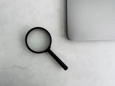 Business person reviewing documents with a magnifying glass at desk
