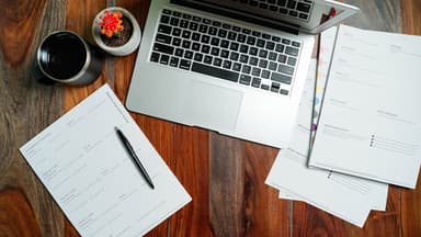Small business owner reviewing contractor tax forms at a desk with a coffee mug and organized folders