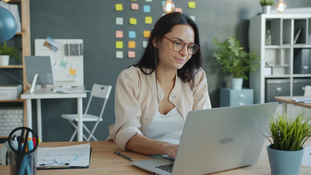 Professional businesswoman typing email on laptop in modern office setting