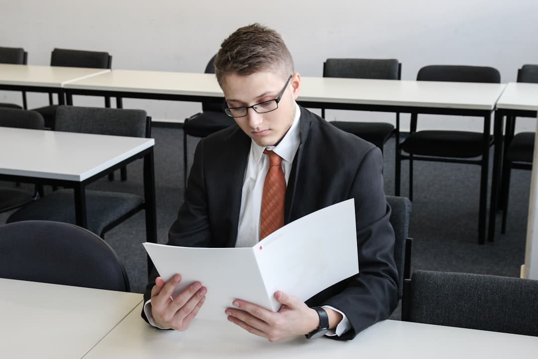 Business professional reviewing contractor documents at desk with laptop and paperwork